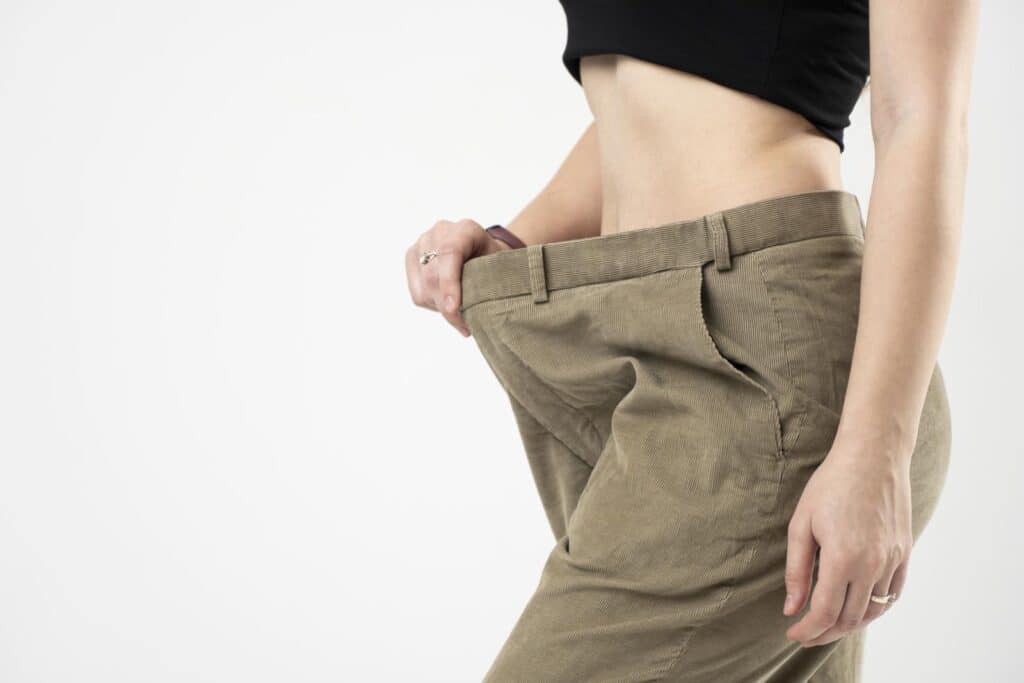 side-view-of-woman-in-beige-oversize-pants-showing-a-result-of-weight-loss-on-white-background-semaglutide-concept-and-weight-loss